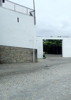 person cleaning the street and white building entrance