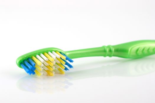 Tooth-brush with green handle over white. Shallow DOF