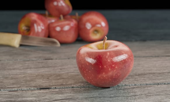 Red apple and blur small knife wood handle on gray wooden surface by 3D rendering