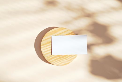 Flat lay of branding identity business name card on wooden and yellow background, light and shadow shape leaves, minimal concept for design