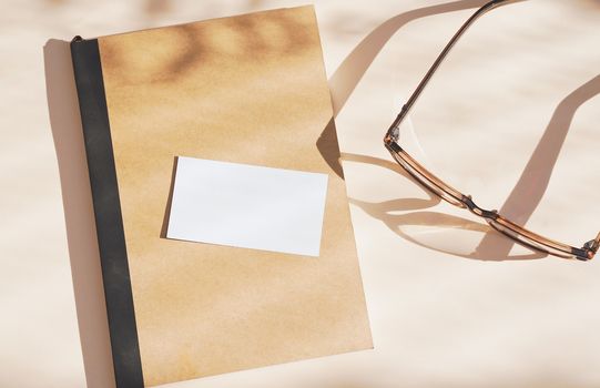 Flat lay of branding identity business name card on notebook with eyeglasses, light and shadow shape leaves, minimal concept for design