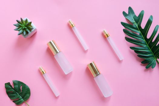 Flat lay of beauty skincare products for mock up in minimal style with plant on pink background