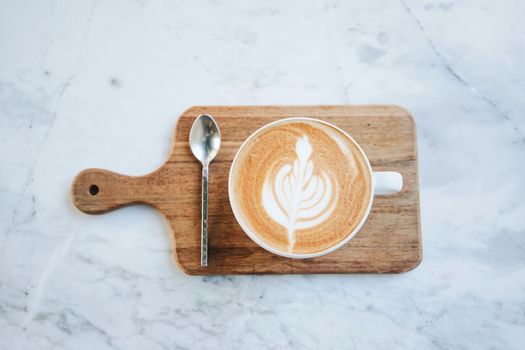 Top view of hot latte coffee on wooden tray on marble table background