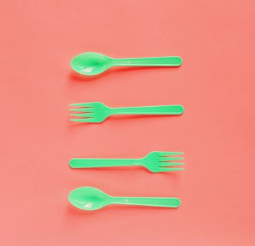 Living Coral color background, Color of the year 2019, Colorful of green plastic spoon and fork on coral background