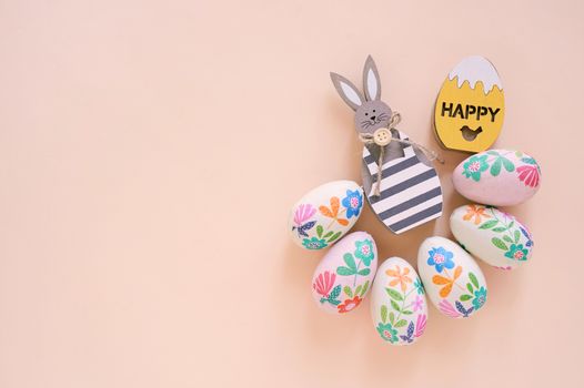 Happy Easter concept with wooden bunny and colorful easter eggs on yellow background. Top view with copy space