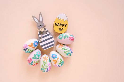 Happy Easter concept with wooden bunny and colorful easter eggs on yellow background. Top view with copy space