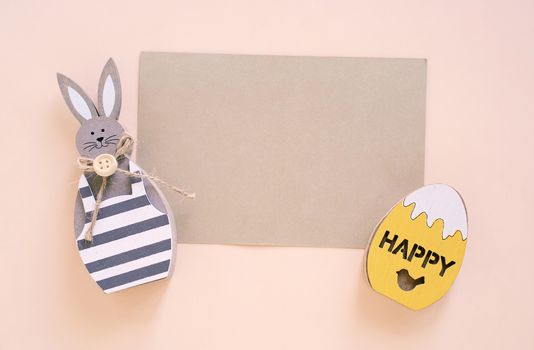 Happy Easter concept with blank card, wooden bunny and colorful easter eggs on yellow background. Top view with copy space