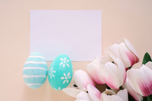 Happy Easter concept with blank card, colorful easter eggs and pink tulips. Top view with copy space