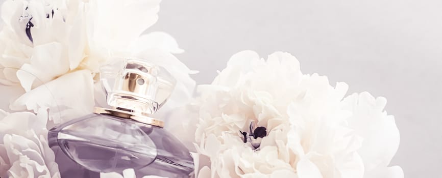 Violet fragrance bottle as luxury perfume product on background of peony flowers, parfum ad and beauty branding design