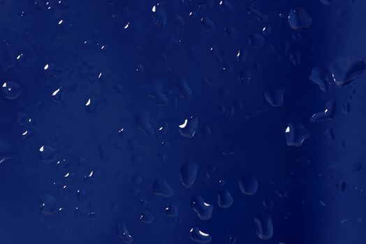 Blue abstract background made drops of water on a glass