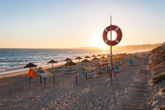 Sunbeds and umbrellas on the Falesia Beach in afternoon sun, Algarve, Portugal