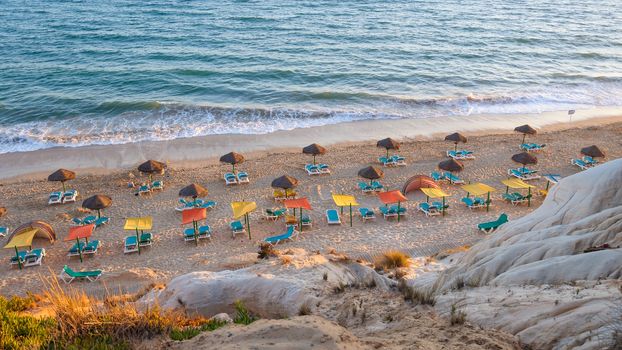 Sunbeds and umbrellas on the Falesia Beach in afternoon sun, Algarve, Portugal