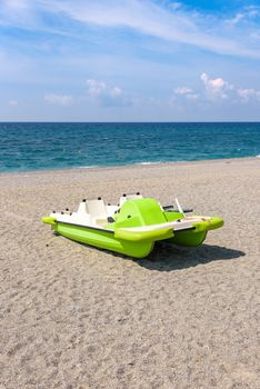 Green pedalo on a gravel beach at the Tyrrhenian Sea in Calabria, Italy