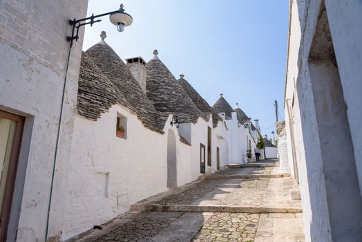 View of narrow picturesque street in Alberobello town, Apulia, Italy