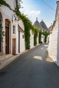 View of narrow picturesque street in Alberobello town, Apulia, Italy