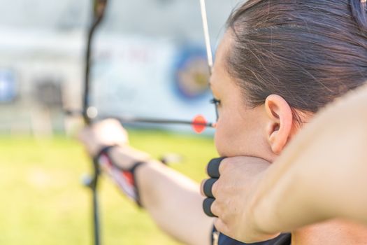 archery, young woman with an arrow in a bow focused on hitting a target.
