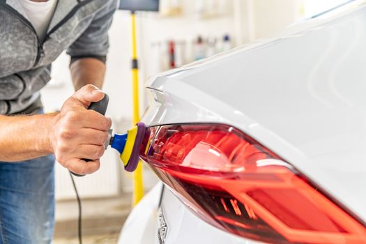 manual polishing of the headlight of luxury cars with the application of protective equipment.