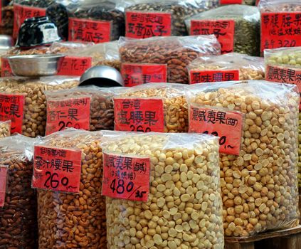 Cashews, macadamia and other nuts for sale at a dry goods market. The signs tell the country of origin and price per catty.
