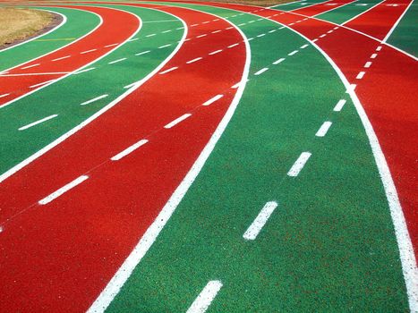 A running track in a stadium with markings in white, red and green and solid and broken lines
