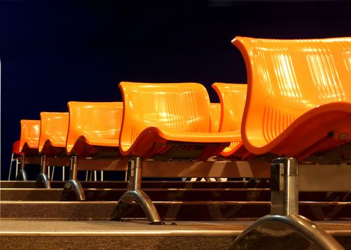 Auditorium or lecture hall with orange plastic chairs in rows