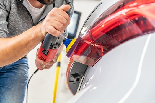 hand polishing car headlights with the help of a hand grinder for better shine.