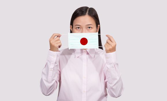 Asian woman wearing hygienic face mask painting Japan flag to protect from the Coronavirus 2019 (COVID-19) infection outbreak situation, the virus originated from Wuhan, China.