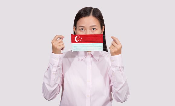 Asian woman wearing hygienic face mask painting Singapore flag to protect from the Coronavirus 2019 (COVID-19) infection outbreak situation, the virus originated from Wuhan, China.