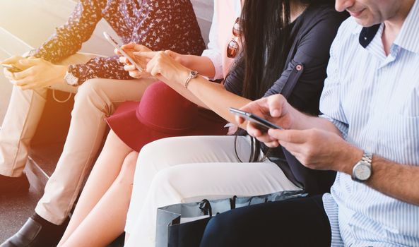 Group of friends sitting outdoors with shopping bags and using smartphone, lifestyle and friendship concept 