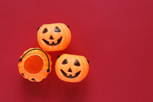 Flat lay style of halloween party concept with decorative plastic pumpkins on red background, copy space 