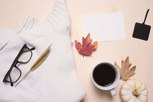 Flat lay of autumn fashion style, sweater, eyeglasses, coffee and blank card with maple leaves, top view
