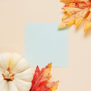 Flat lay of minimal workspace blank notebook with autumn leaves and pumpkin on yellow background, autumn and thanksgiving concept