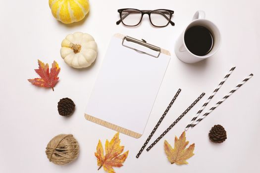 Flat lay of autumn or thanksgiving style concept with coffee, autumn leaves, pumpkins, coffee and clipboard on white background