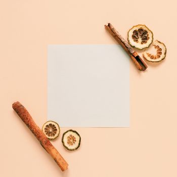 Flat lay of blank paper with cinnamon sticks and herb on yellow background, autumn and thanksgiving concept, minimal style