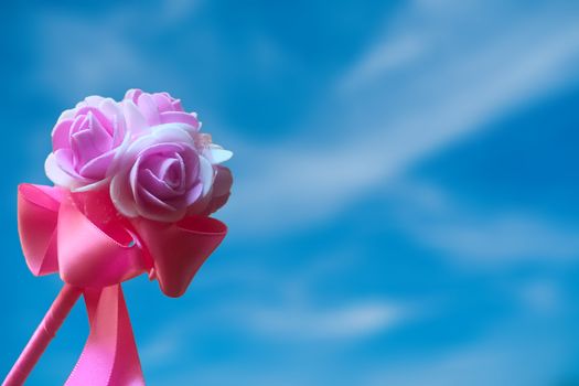 Artificial pink rose with blurred sky background
