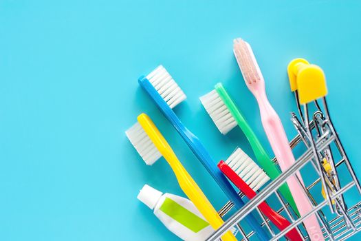 Shopping cart with toothbrush and toothpaste on blue background for market and dental care concept