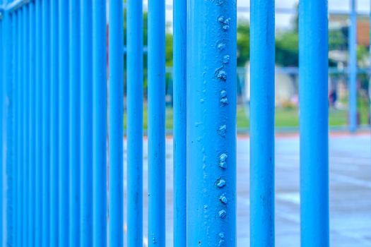 Blue steel fence around soccer field with rough surface textured
