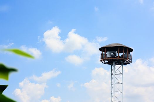 Public speaker tower against cloudy and blue sky background for announcements and alarms