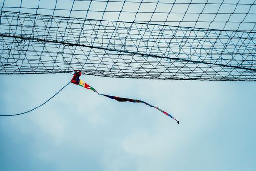 Rag tied to the net blowing in sport field similar to windsock to show the direction and strength of the wind against cloudy sky in the blue day
