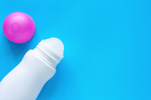 Female deodorant or roll on bottle with pink cover on blue background for body skin care concept