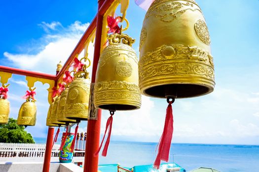 Golden bells in shrine with blue sky and sea view