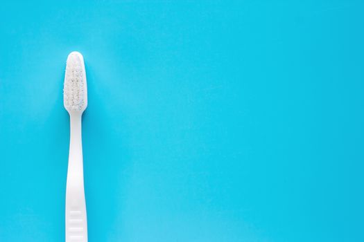 White toothbrush used for cleaning the teeth on blue background for dental care concept