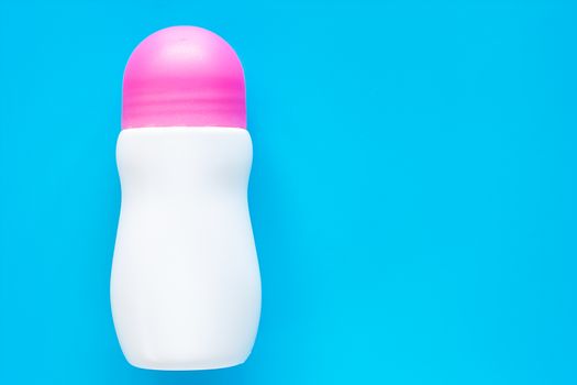 Female deodorant or roll on bottle with pink cover on blue background for body skin care concept