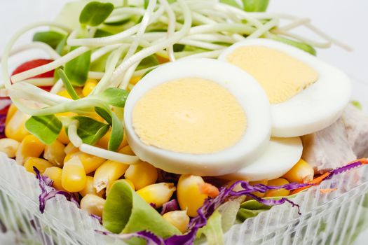 Close up of boiled chicken egg with fresh salad vegetable for healthy eating and diet food concept