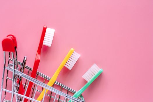 Shopping cart with toothbrush on pink background for market and dental care concept