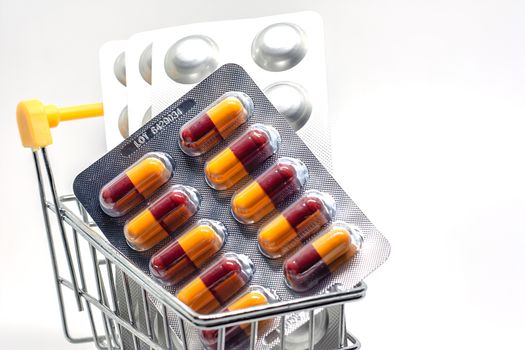 Medicine, pills, drug or tablets in a blister pack in shopping cart on white background for healthcare and medical concept
