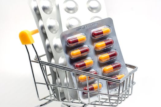 Medicine, pills, drug or tablets in a blister pack in shopping cart on white background for healthcare and medical concept