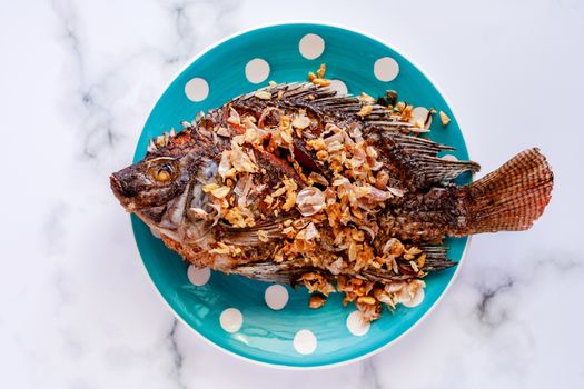 Delicious fried Tilapia fish in polka dot plate on marble background for tasty food concept