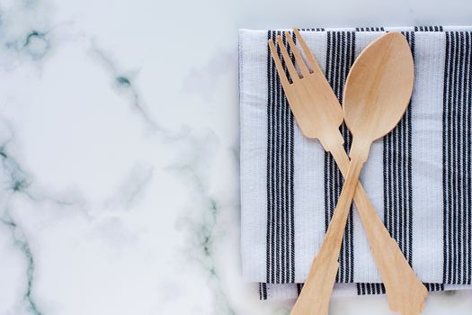 Wooden spoon and fork with napery on marble background for utensil and kitchenware concept