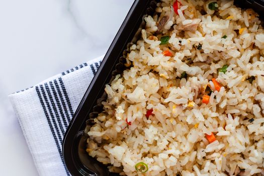 Delicious fried rice in lunch box with napery on marble background for ready to eat and food concept
