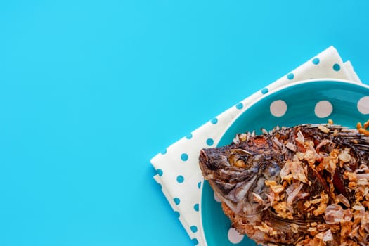 Delicious fried Tilapia fish in polka dot plate on blue background for tasty food concept